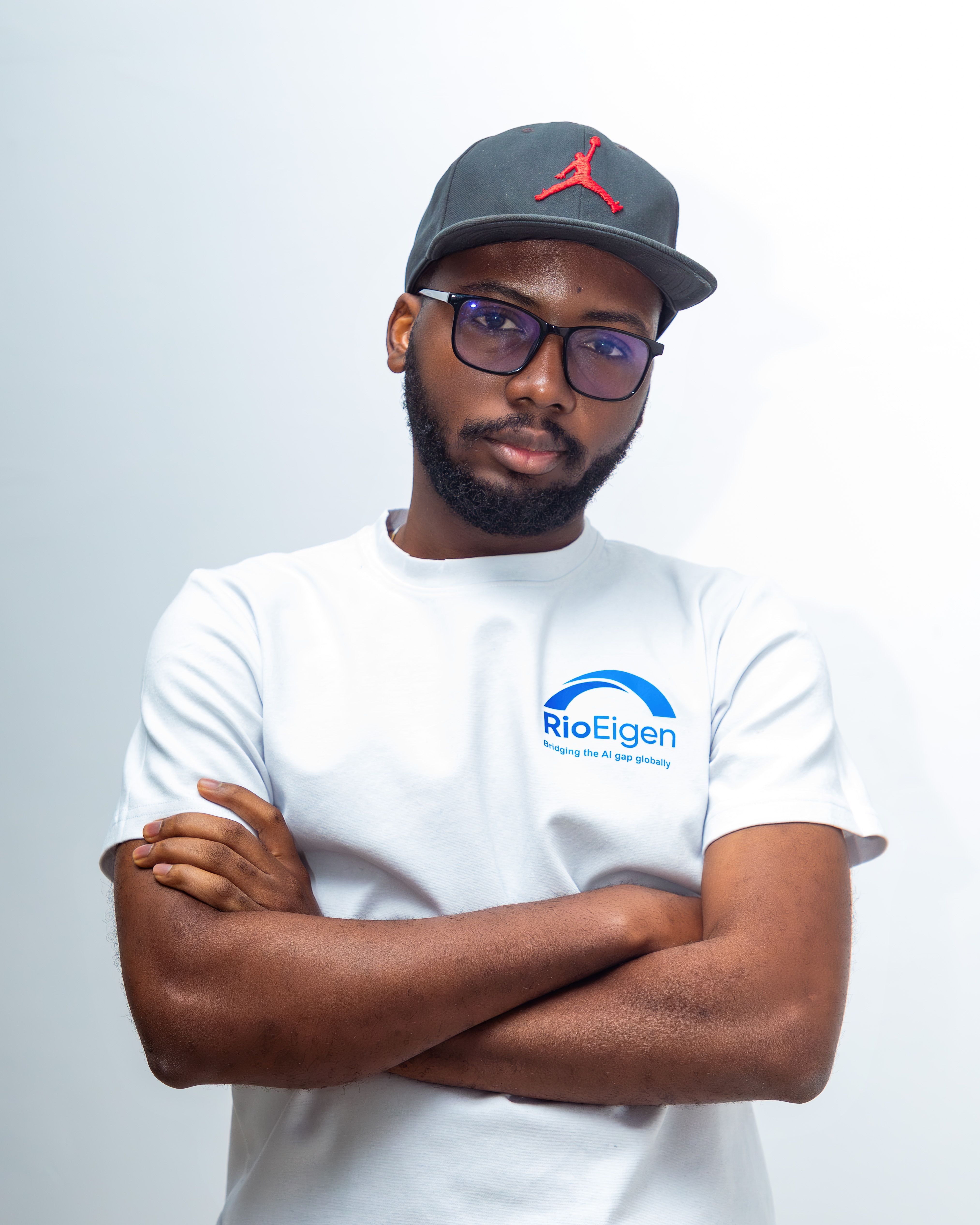 Portrait of a young man wearing a cap and glasses with arms crossed, looking confident.
