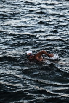 Swimmer practicing freestyle stroke in open water during daytime.