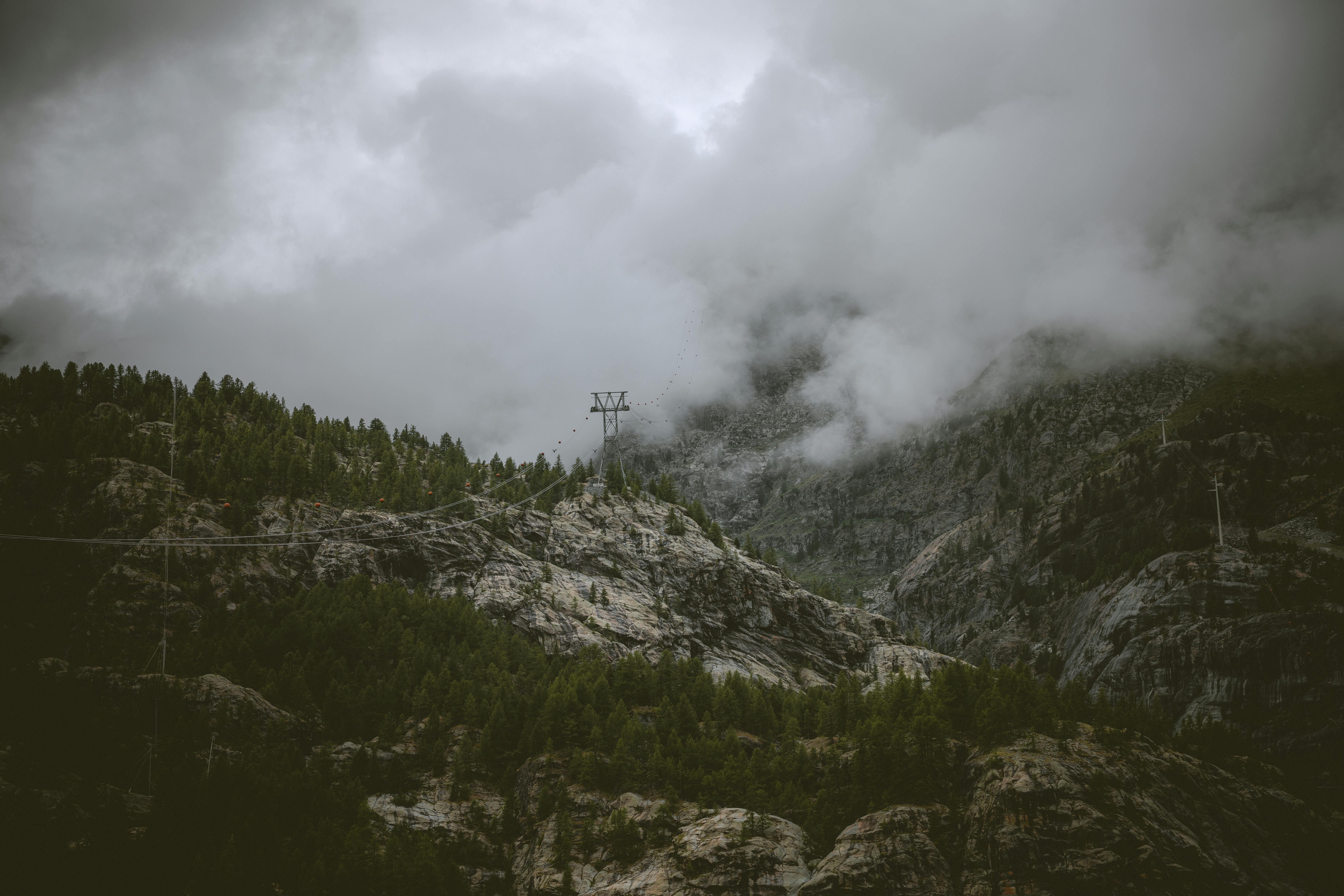 Dramatic misty view of alpine mountains near Zermatt with cloudy skies and lush greenery.