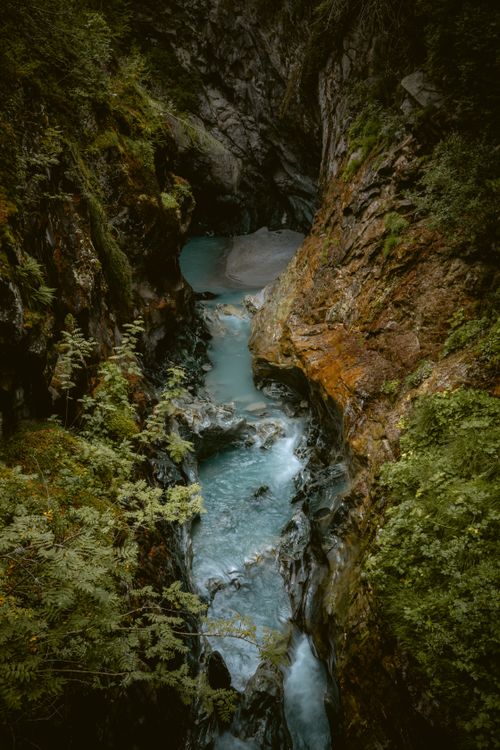 Free Tranquil view of a rocky gorge with a flowing stream, surrounded by lush greenery in Zermatt, Switzerland. Stock Photo