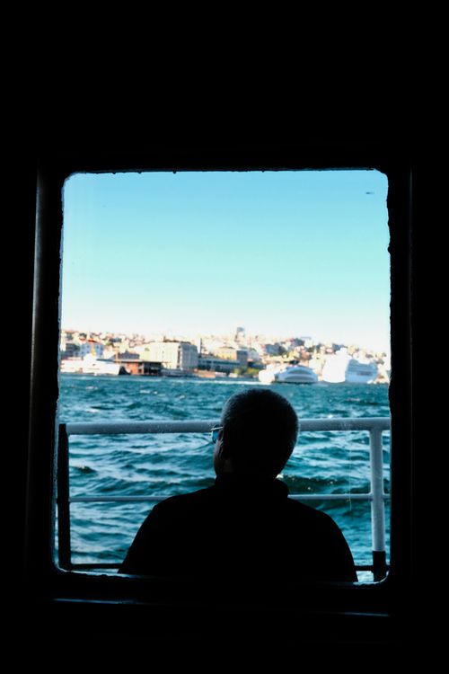 Free Silhouette of man looking at cityscape from a ferry window on a sunny day. Stock Photo