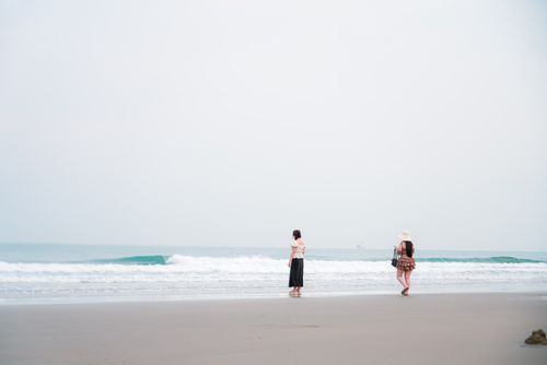 Free Two women enjoying a peaceful walk on a serene beach during summer, capturing the essence of relaxation and travel. Stock Photo