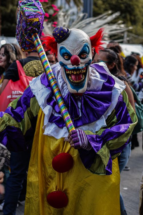 Free Frightening clown in colorful costume holding a hammer at an outdoor festival parade. Stock Photo
