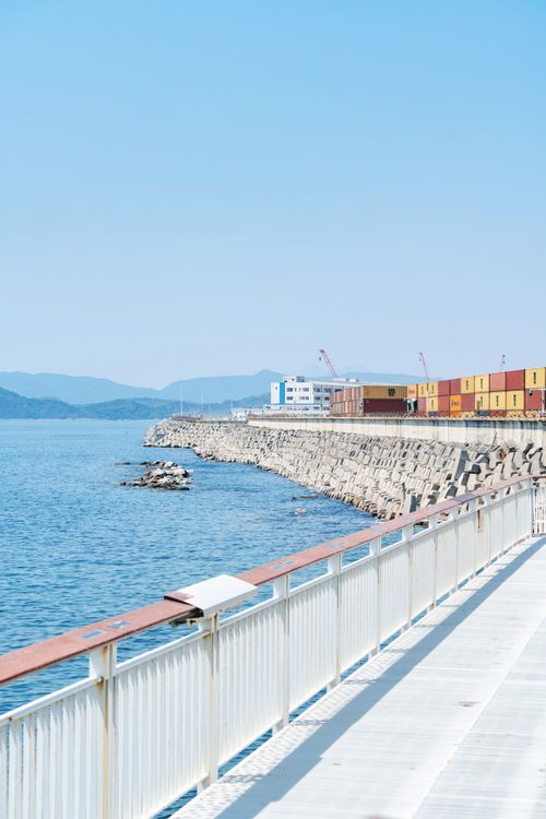 Free Peaceful ocean scene with colorful cargo containers by the shore. Stock Photo