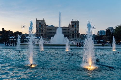 Free Beautiful illuminated fountains in front of historic buildings at dusk, capturing a serene urban scene. Stock Photo