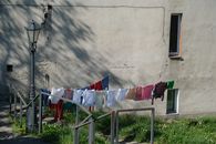 A vibrant array of clothes drying outdoors on a sunny day, against a textured wall.