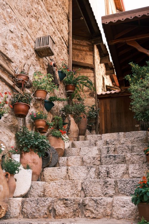 Free Rustic stone staircase adorned with lush potted plants in a Mediterranean setting. Stock Photo