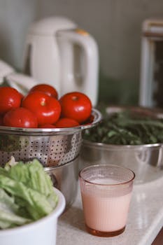 A fresh array of tomatoes and lettuce next to a juicer on a kitchen counter.