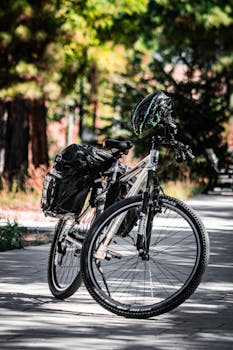 A mountain bike parked on a shaded forest path with a helmet and backpack.