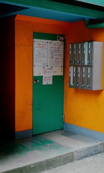 Colorful street scene in Tokyo's Kita Ward featuring a green door and orange walls with mailboxes.