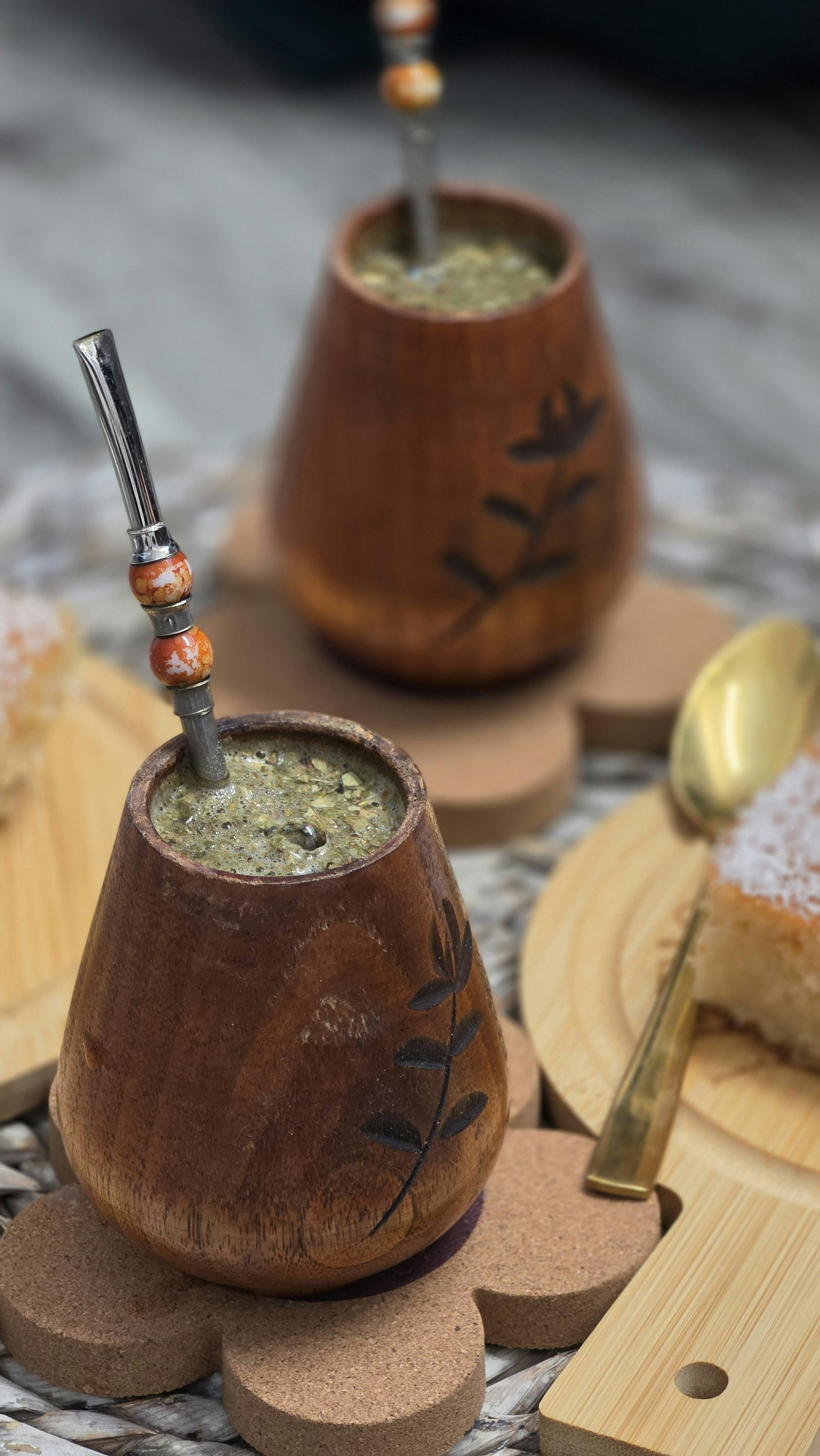 A warm setting with yerba mate in carved wooden cups and cake slices on wooden plates.