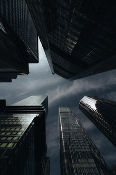 A powerful view of towering skyscrapers reaching into a moody, overcast sky.