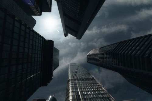Free Looking up at tall skyscrapers against a cloudy sky, creating a dramatic urban scene. Stock Photo
