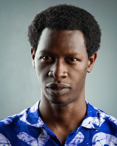 Free Close-up portrait of a confident young man in a blue patterned shirt against a gray background. Stock Photo