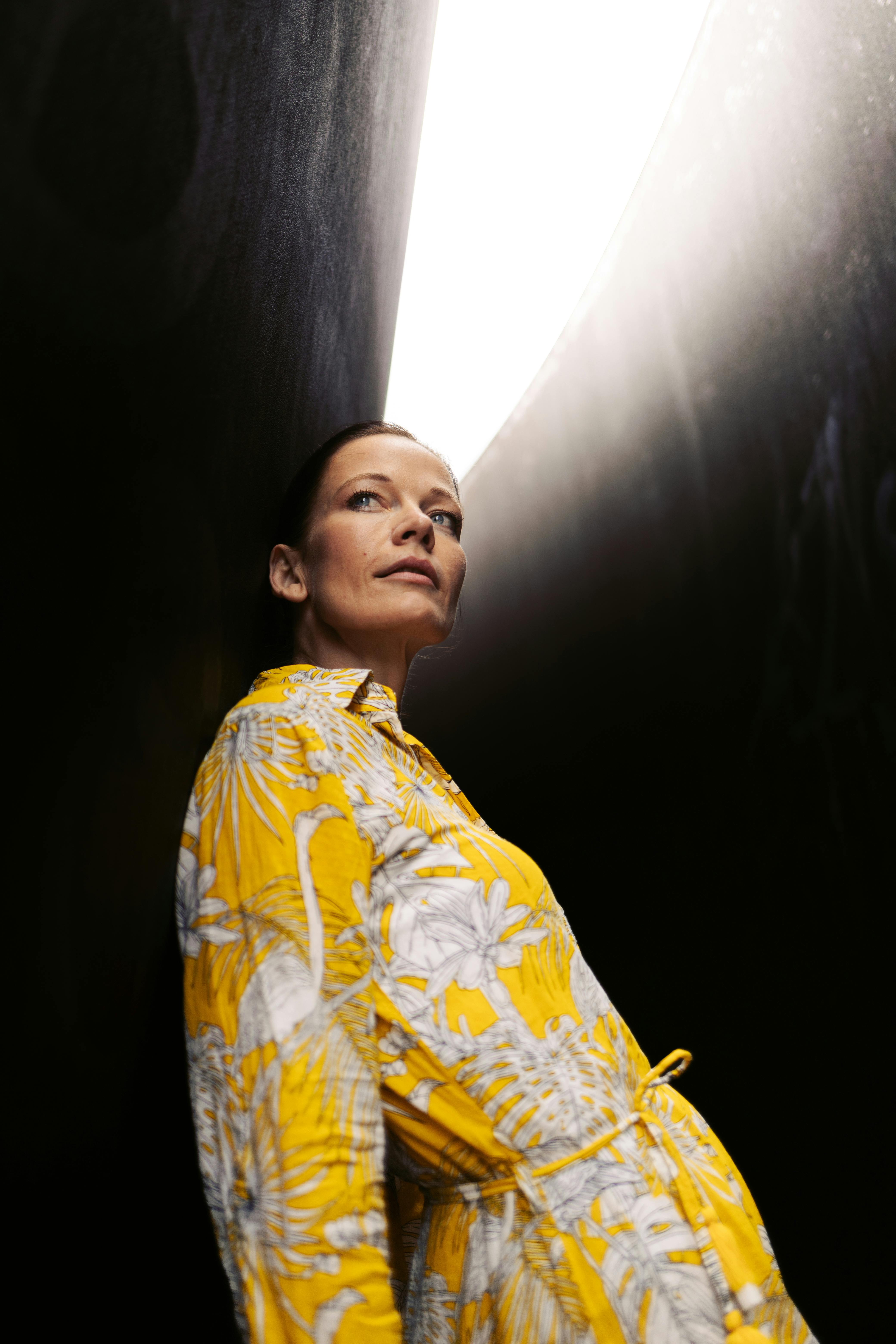 Portrait of a woman in yellow dress against a dramatic light background in Berlin.