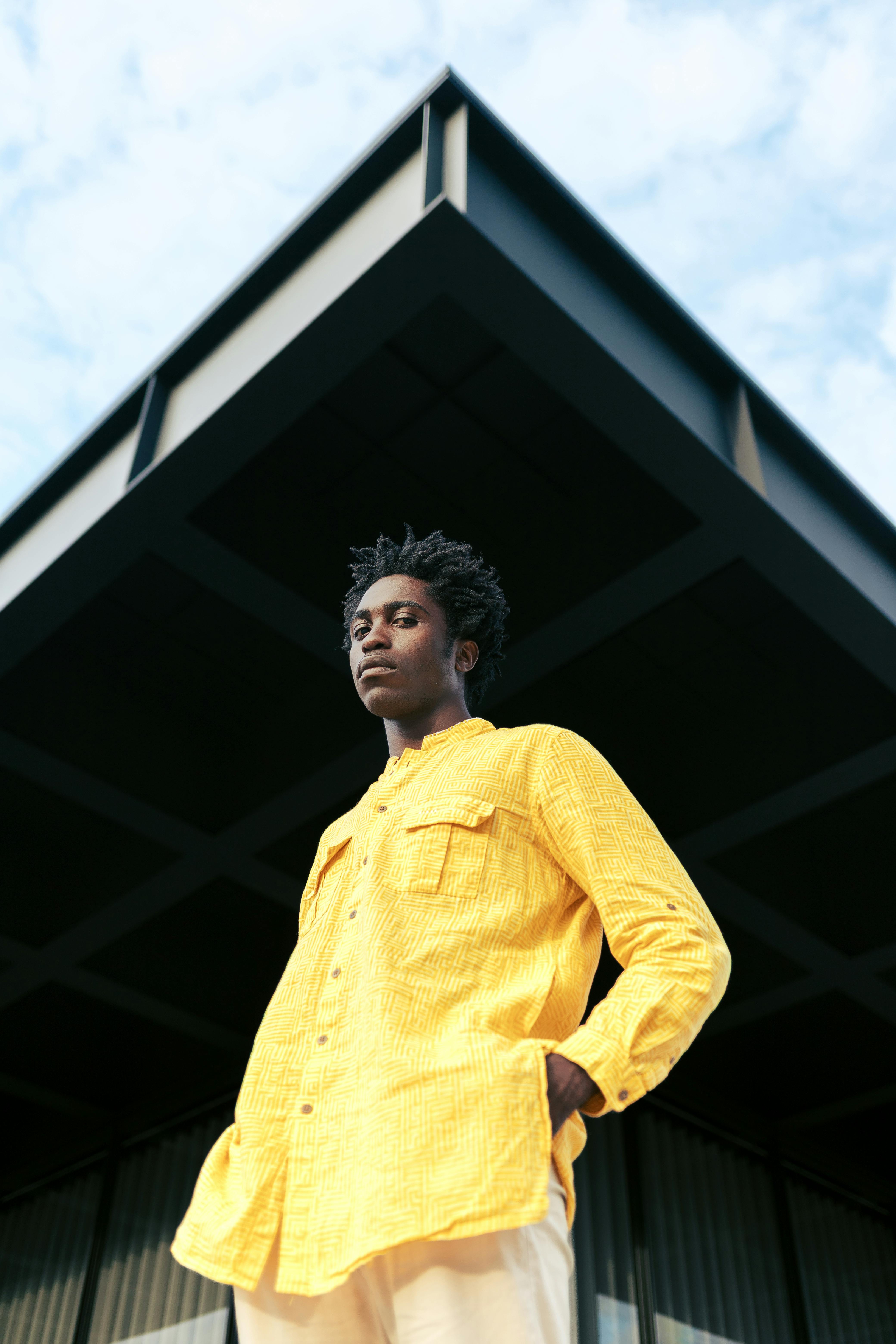 Portrait of an individual in a yellow shirt against modern architecture in Berlin, Germany.