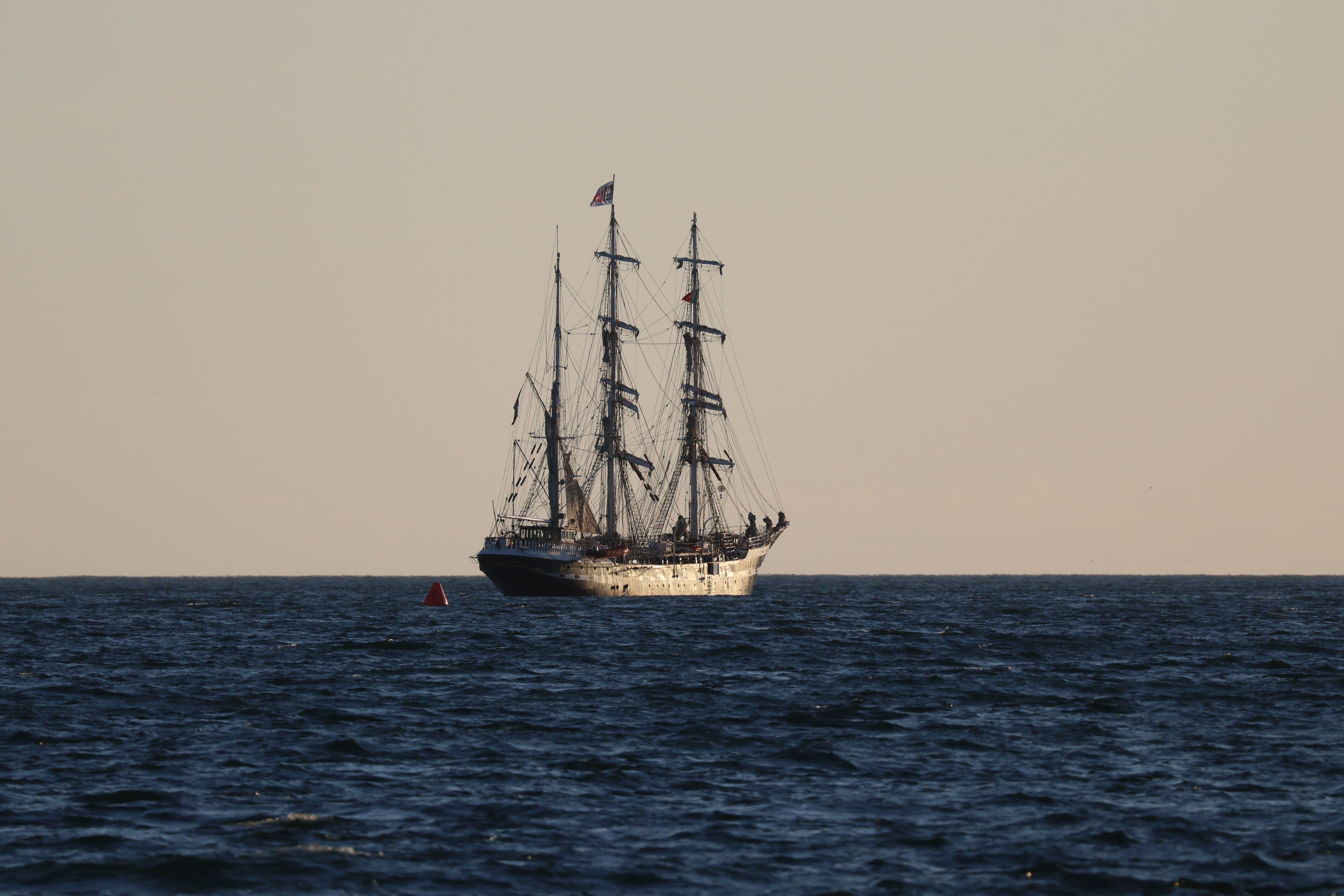 A stunning tall ship sails quietly on a serene ocean under a clear sky.