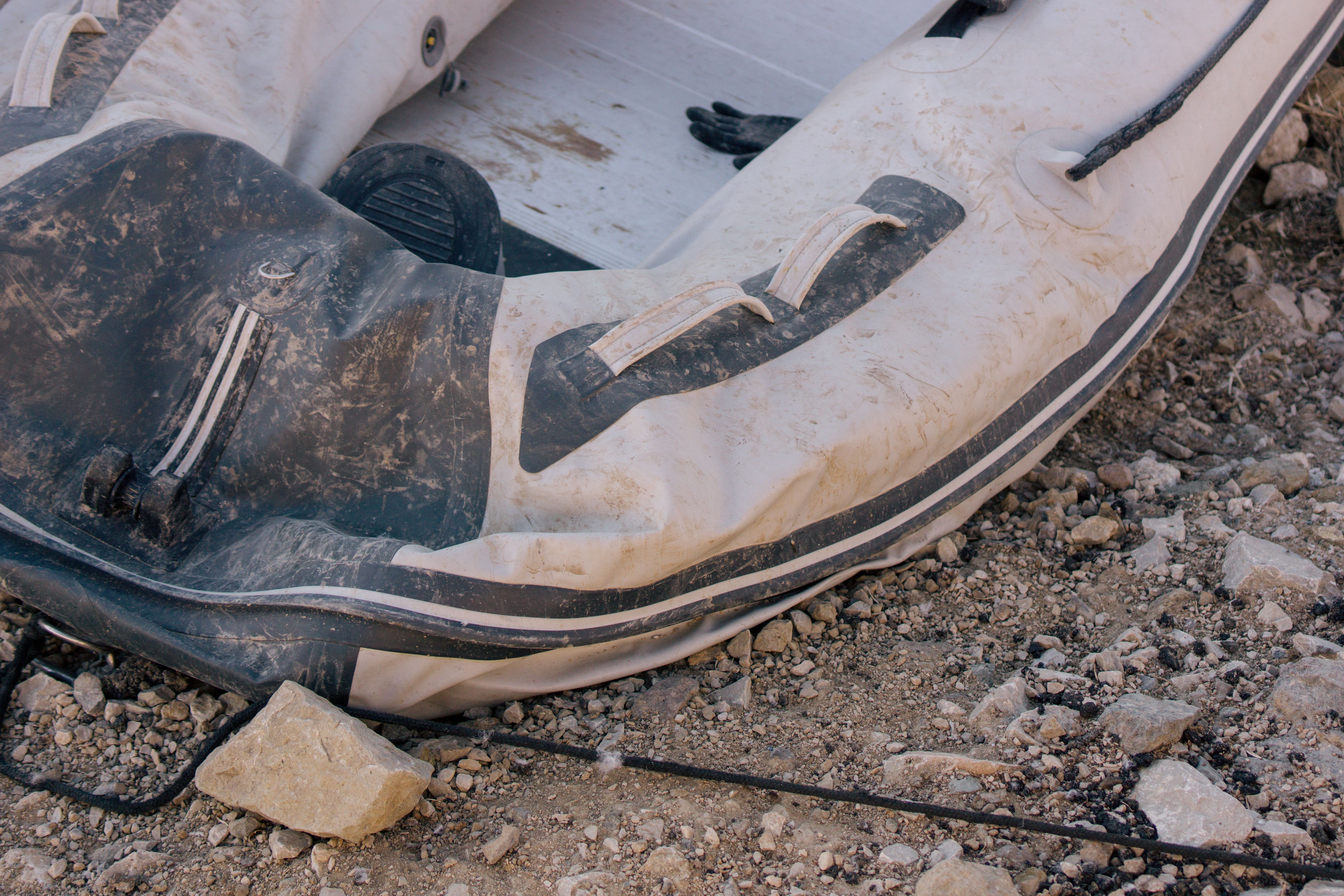Close-up view of a weathered inflatable boat resting on a rocky beach, conveying adventure.