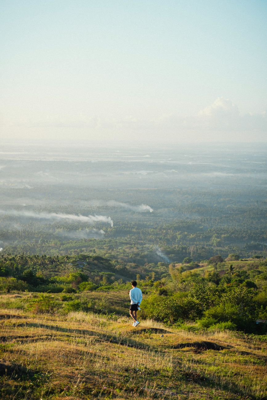 A lone person enjoying a scenic view over a misty landscape during sunrise.