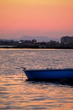 A tranquil evening scene with a boat on a lake during sunset, highlighting the warm, calming atmosphere.