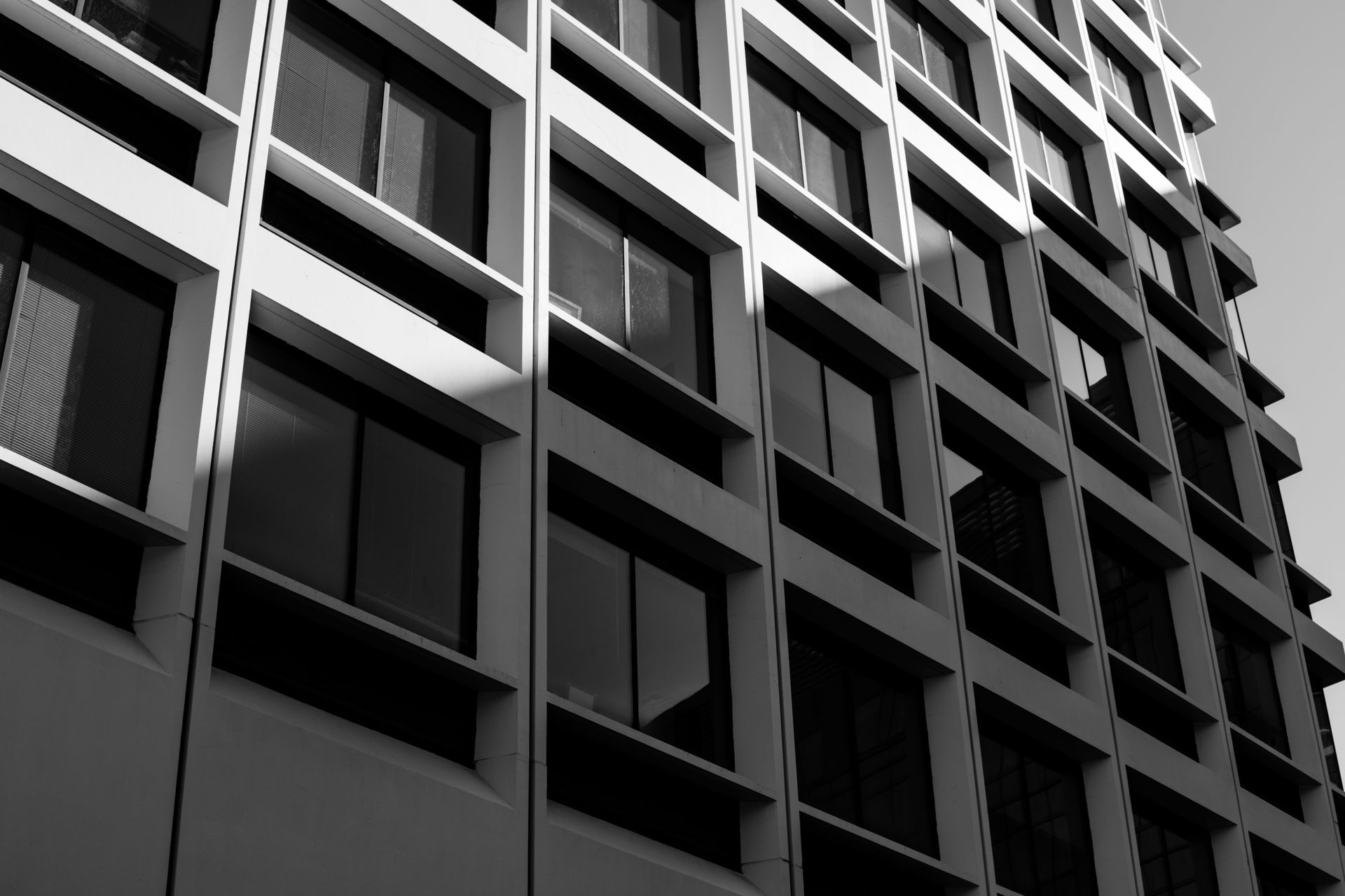 Grayscale view of a modern building exterior with geometric patterns and shadows.
