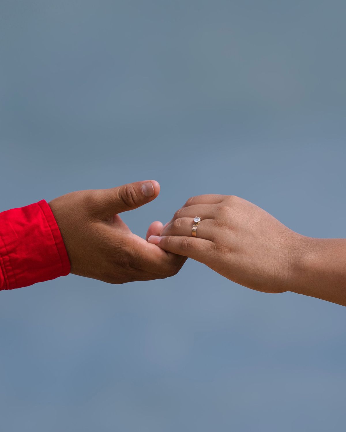 Two hands reaching toward each other against a blue background, symbolizing the relationship dynamic people have with money