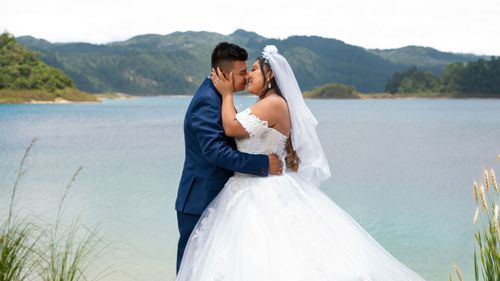 Free Bride and groom sharing a kiss by a beautiful lakeside view. Stock Photo
