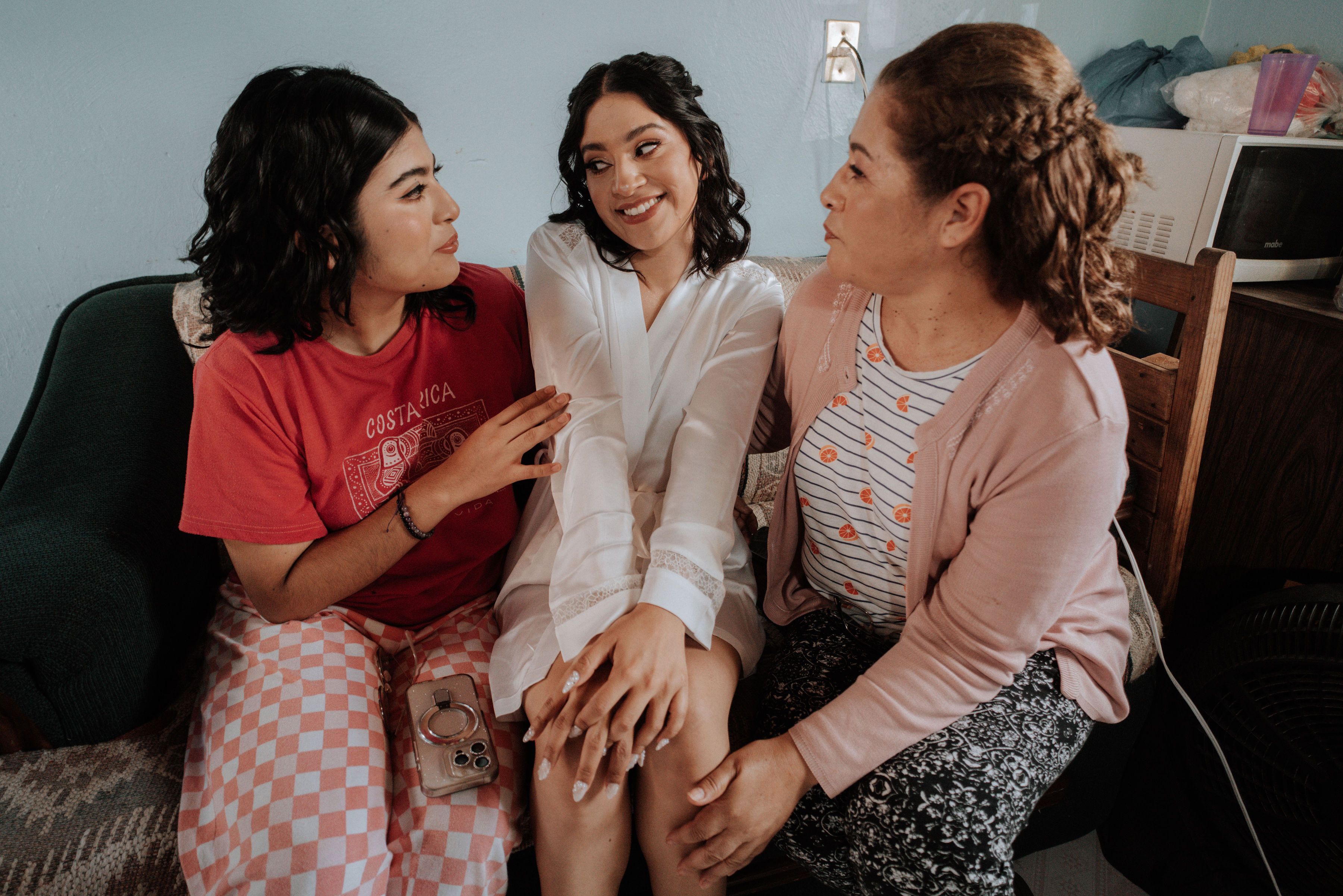 Three women sitting indoors sharing a joyful moment in a casual setting.