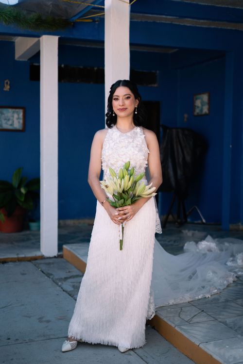 Free Elegant bride with a lily bouquet poses in a bright, modern setting, indoors. Stock Photo