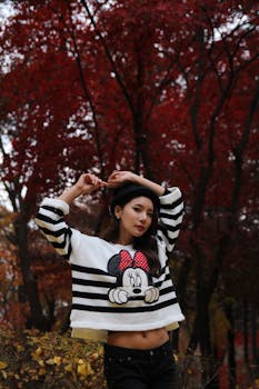 一位穿着条纹毛衣的时尚女士，以充满活力的秋叶为背景