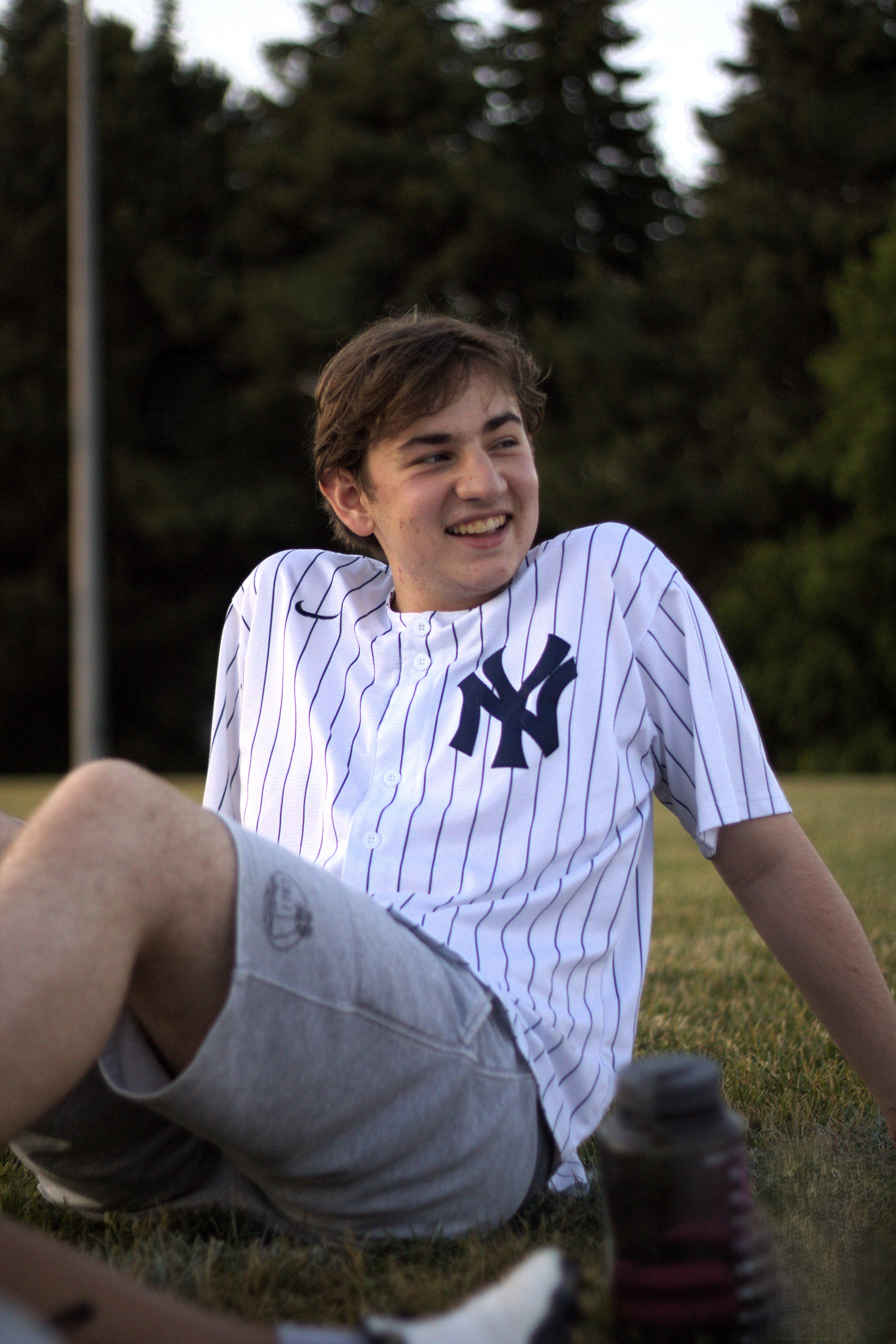 Teenage boy enjoying a relaxed moment outdoors in casual sportswear, embodying youthful leisure.