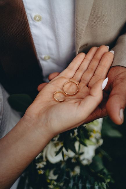 Intimate close-up of wedding rings held by the bride, capturing a beautiful moment.