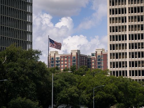 Free American flag waving between Houston skyscrapers on a sunny day. Stock Photo