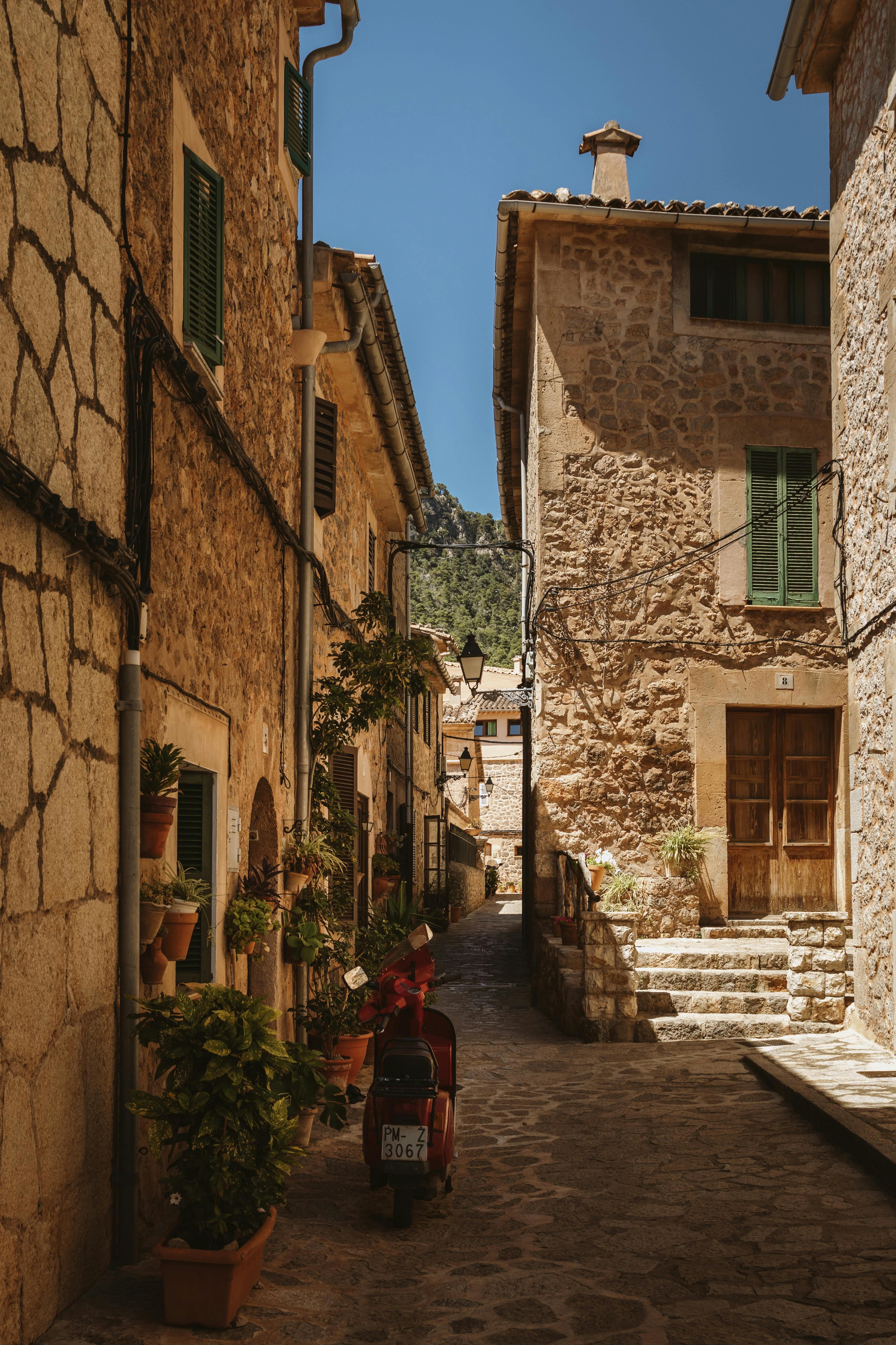 Quaint cobblestone street in Valldemossa with stone houses and a scooter.