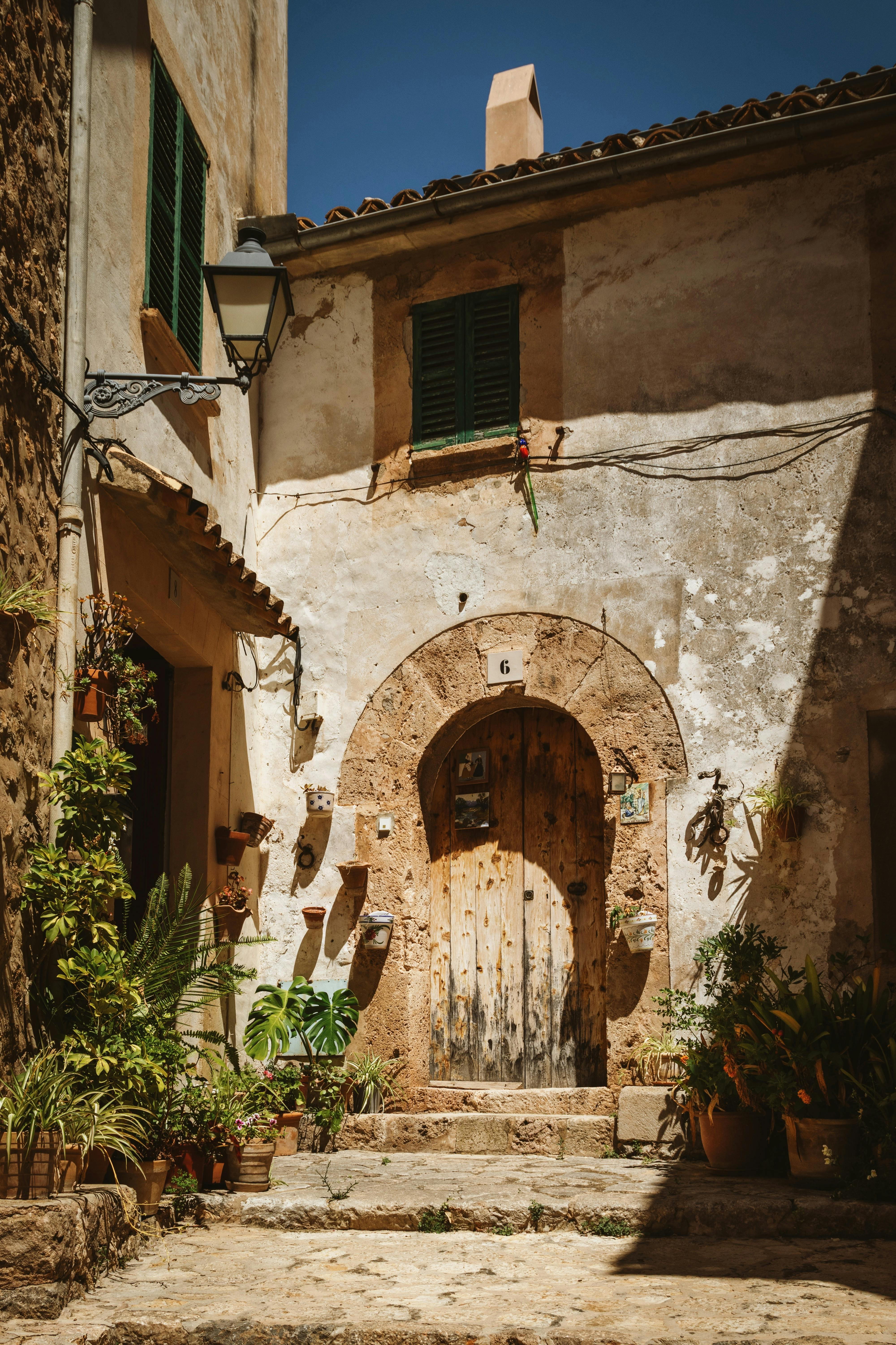 Explore the rustic charm of Valldemossa with this picturesque Mediterranean doorway bathed in sunlight.