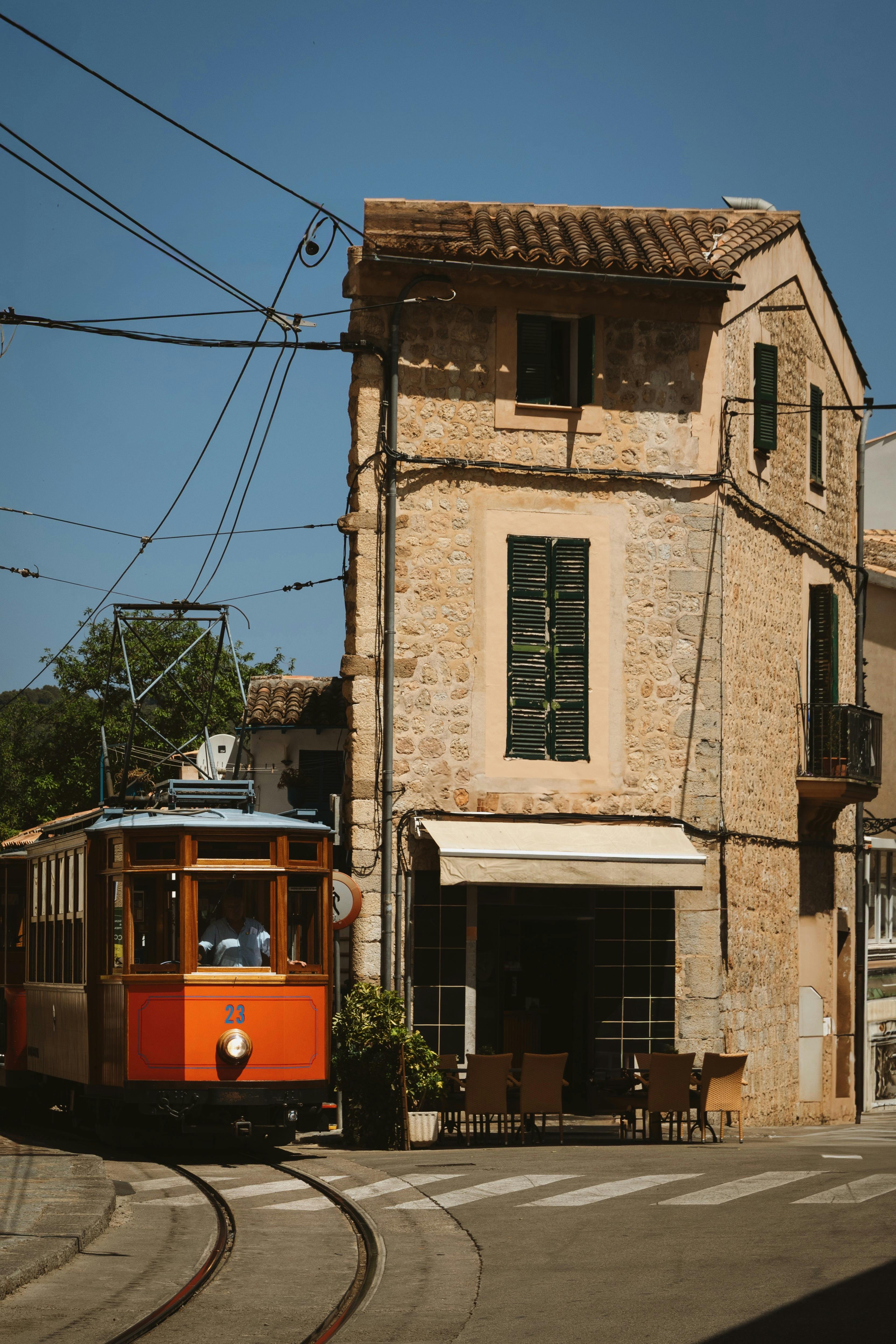 Capture of the historic Sóller tram in front of a classic stone building in Sóller, Spain.
