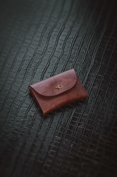 A stylish leather pouch rests on a black textured background, showcasing elegant design and craftsmanship.