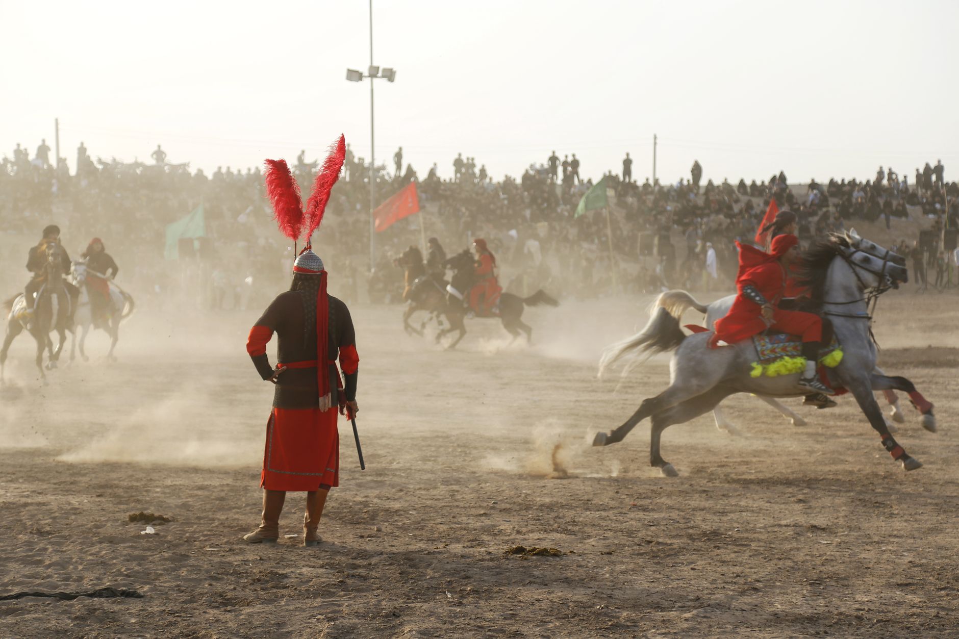 A dramatic scene of a historical reenactment with horsemen in traditional attire during the day.