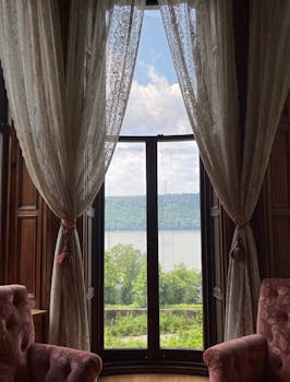 Elegant room featuring French doors with lace curtains opening to a picturesque landscape.