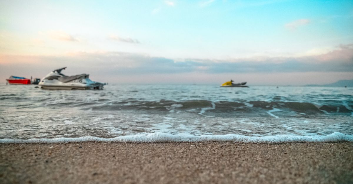 Jet skis on an inviting sandy beach with gentle ocean waves at dusk. Perfect for seaside adventures.