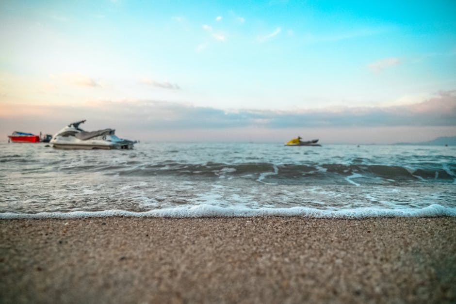 Jet skis on an inviting sandy beach with gentle ocean waves at dusk. Perfect for seaside adventures.