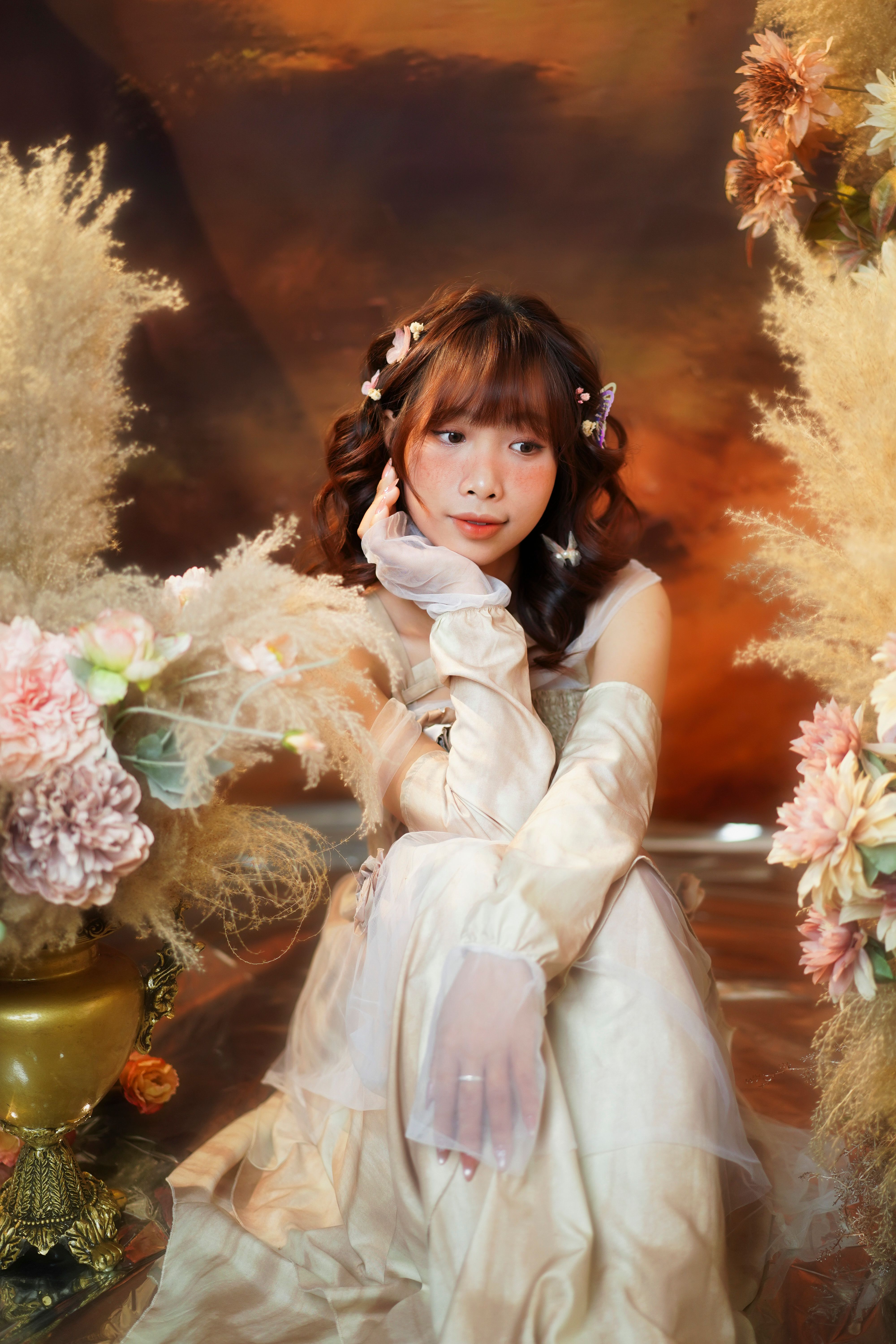 Elegant woman posing among peach and cream flowers, exuding grace and timeless beauty.