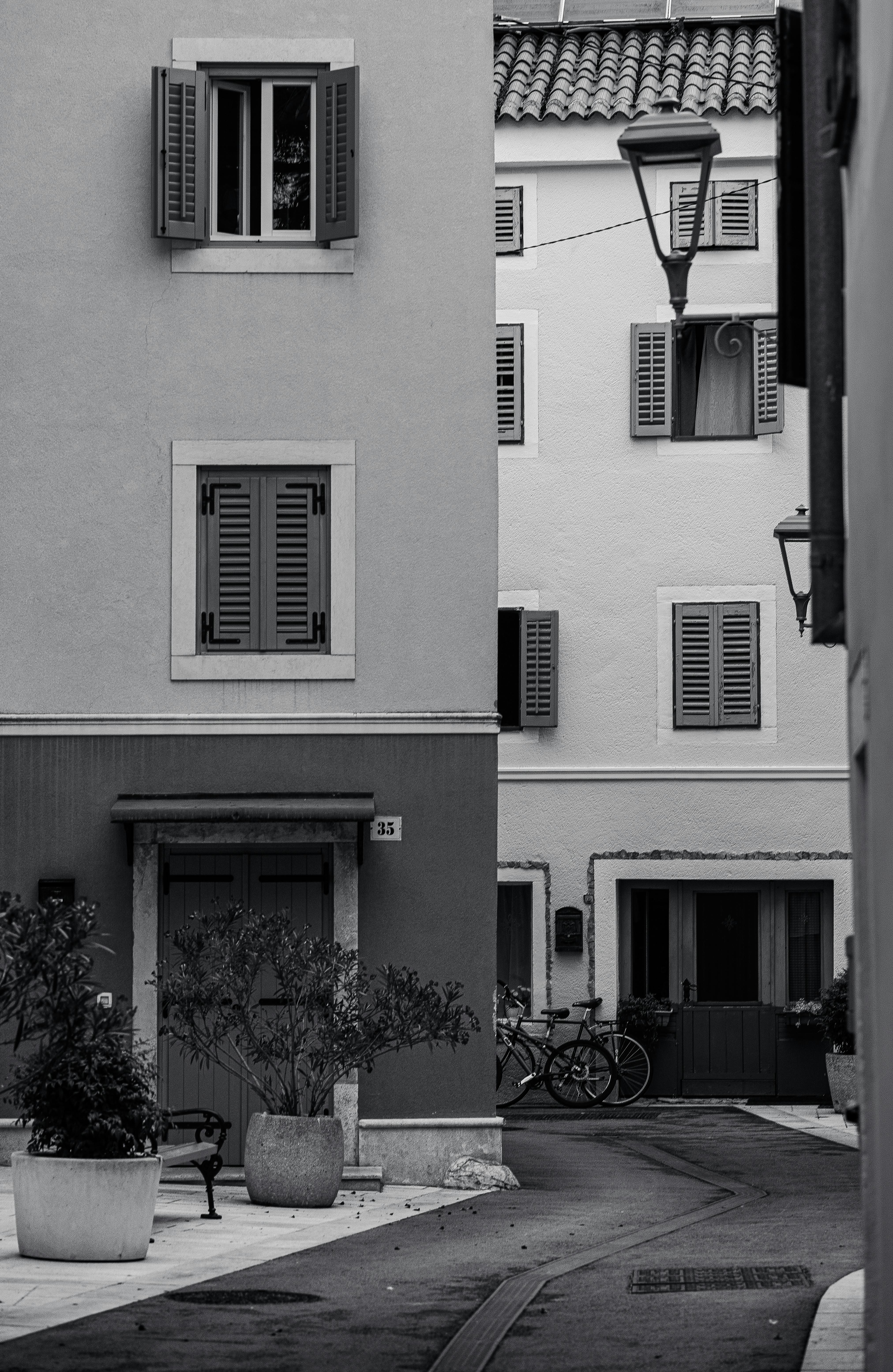 Free Charming European street with vintage architecture, shutters, and bicycles in a black and white setting. Stock Photo