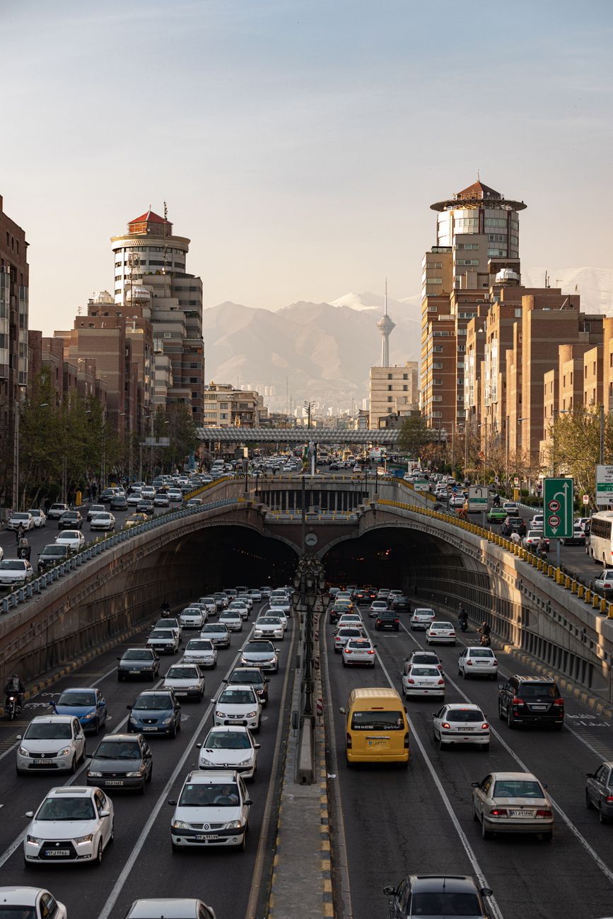 Traffic moves through Tehran with the Milad Tower rising over the city.