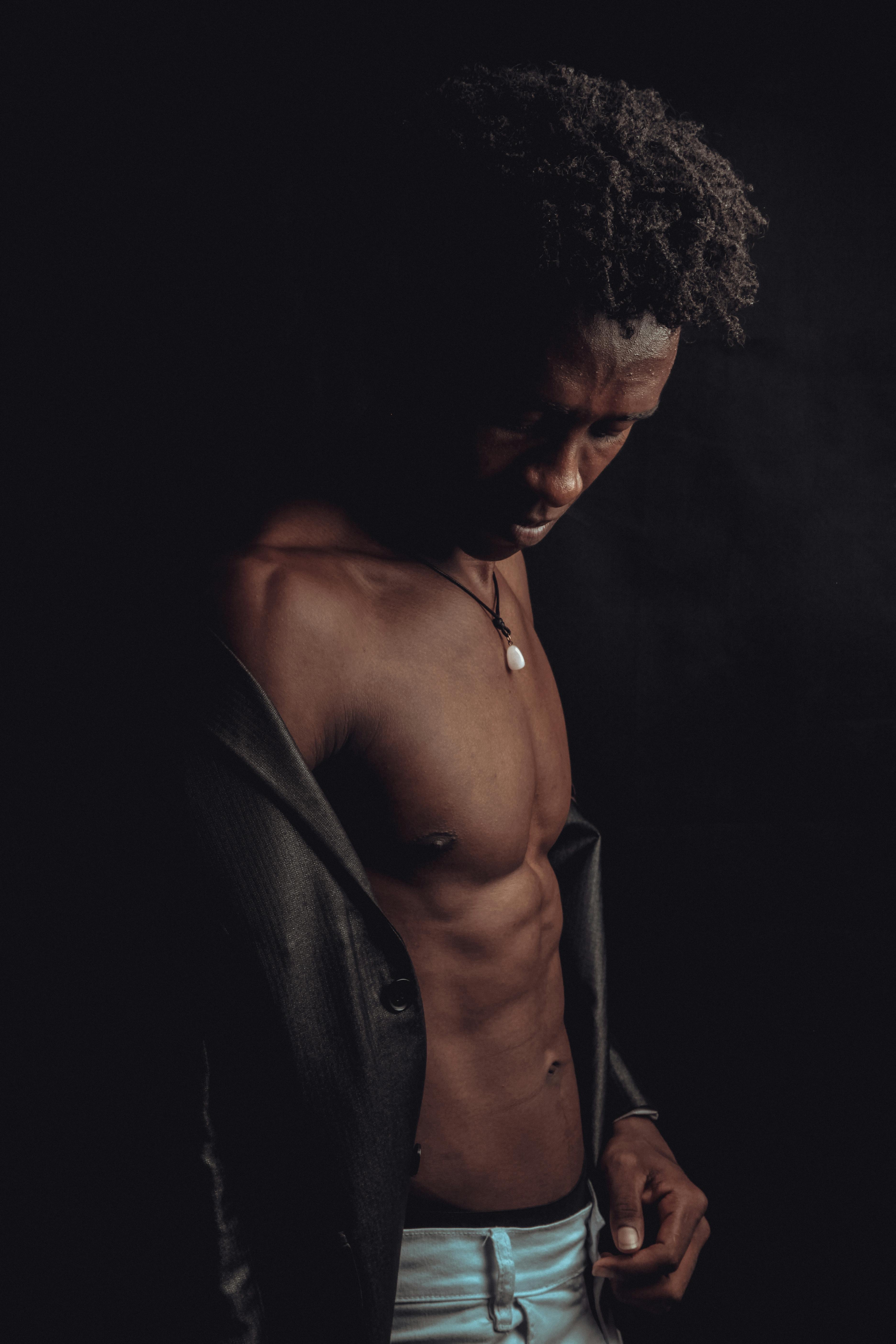 Free Artistic portrait of a young man showcasing muscle definition in dramatic lighting. Stock Photo