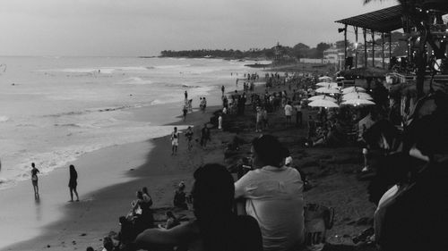 Free Black and white photo of a crowded beach at sunset, capturing silhouettes and waves. Stock Photo