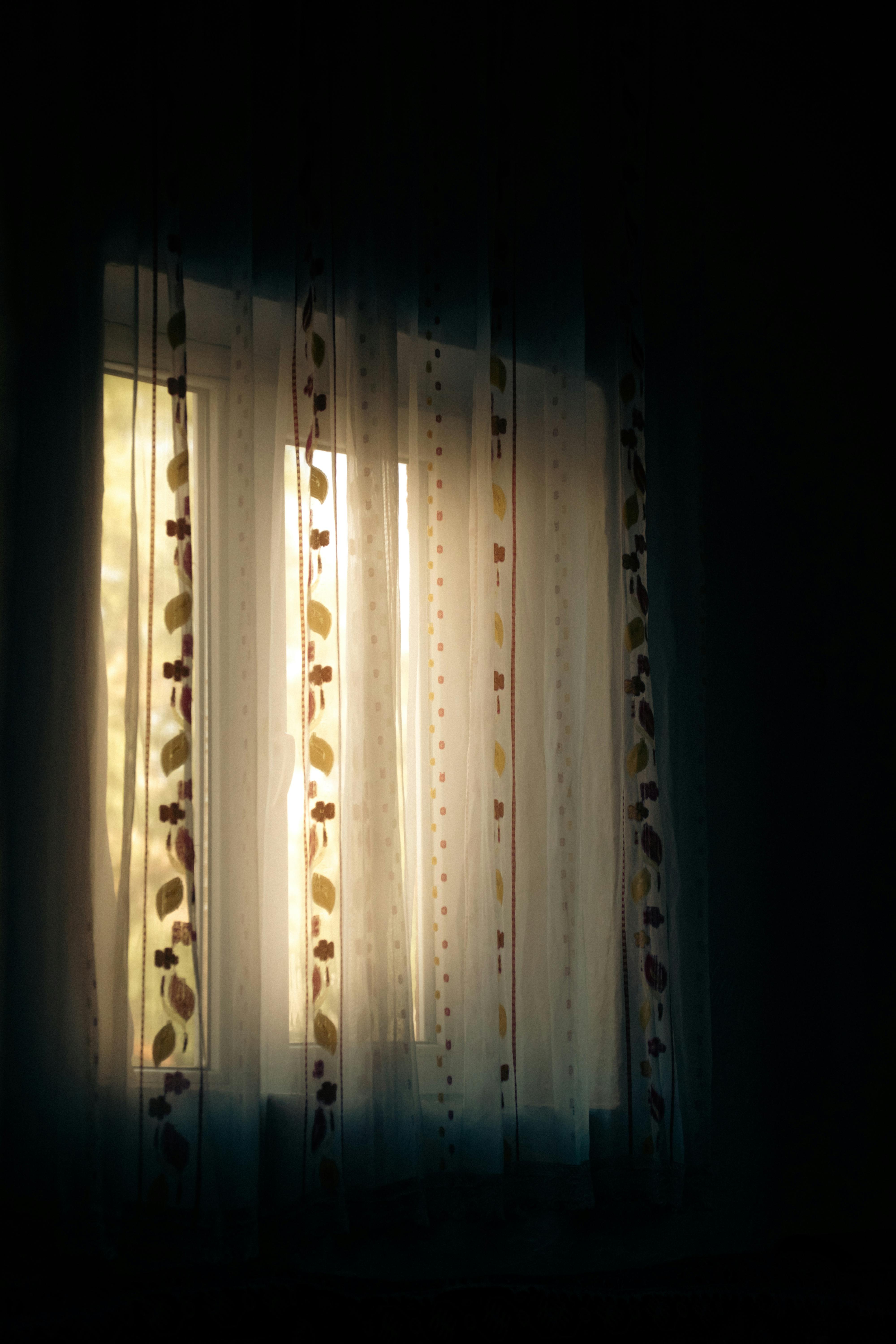 Gratuit Lumina blândă a dimineții se filtrează prin perdelele cu modele florale, creând o ambianță interioară senină. Fotografie de stoc