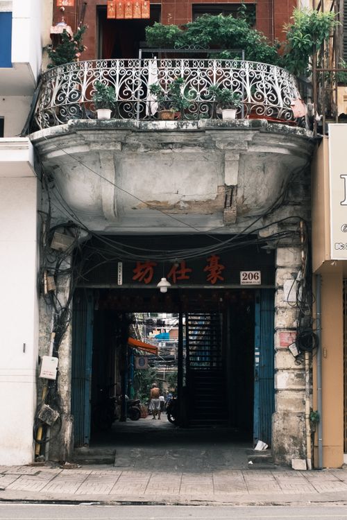 Free Historic urban building entrance with plants and intricate balcony railing, showcasing vintage architecture. Stock Photo