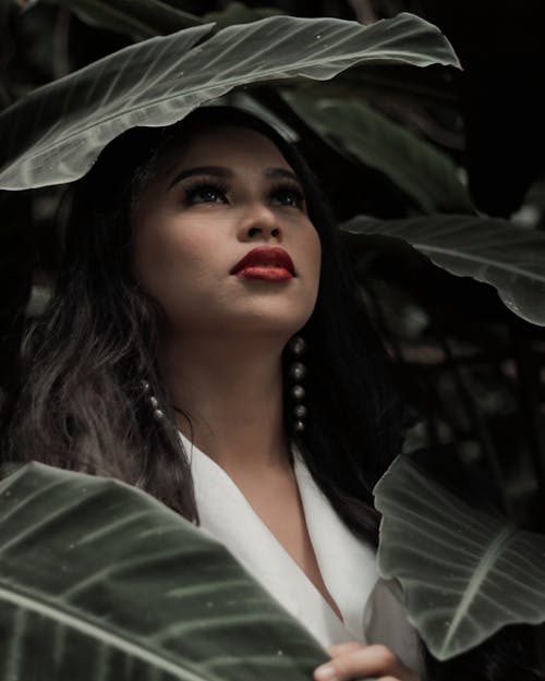 Shallow Focus Photo of Woman Wearing White Top Beside Green Plants