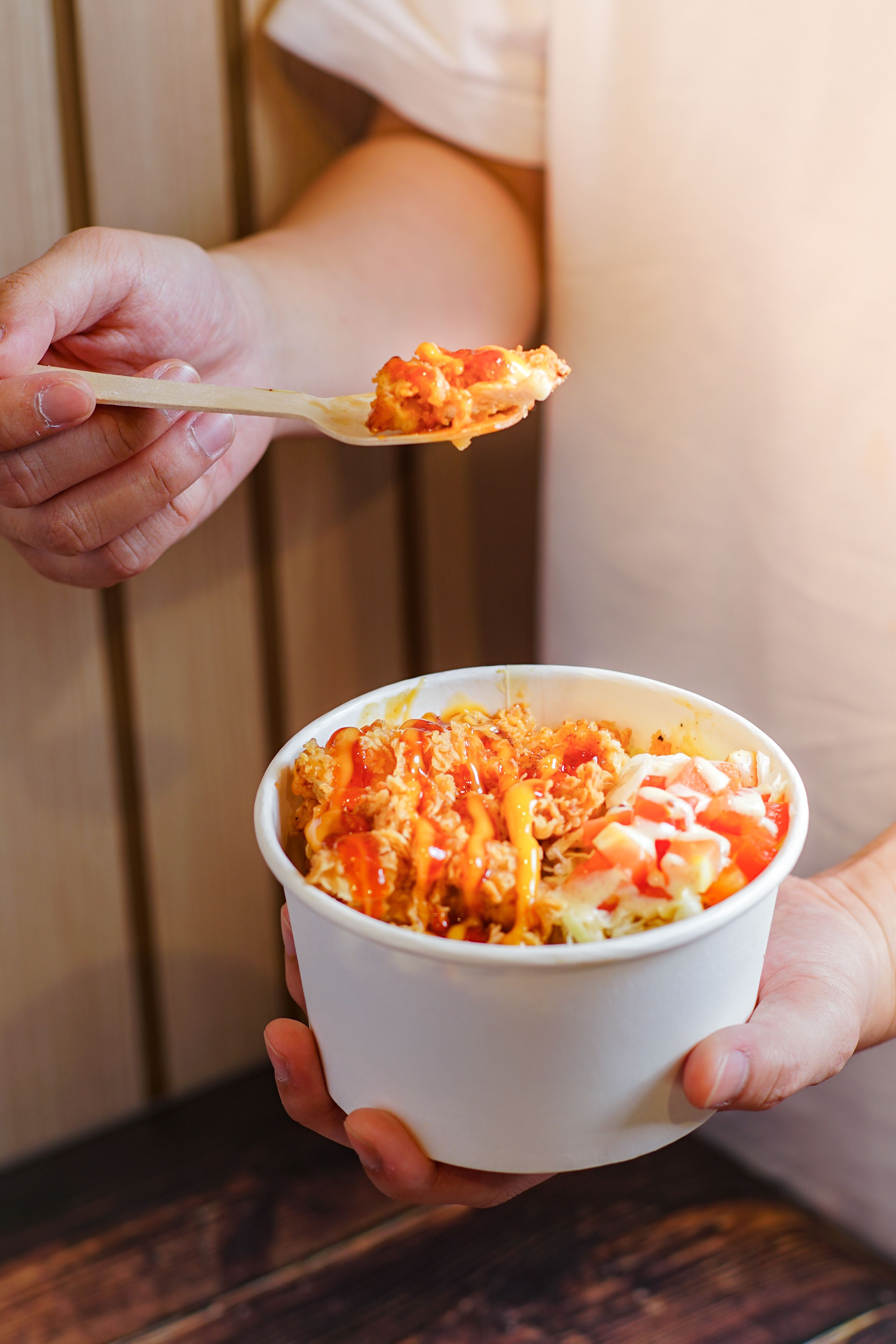 Tempting chicken rice bowl topped with chili and creamy sauce, offering a burst of flavors.